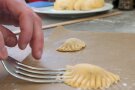 Die Ränder von Raviolis werden mit einer Gabel zusammengedrückt.