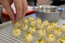 Weiße Pralinen werden mit Pistazien verziert.