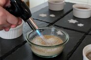 Eine Creme Bruillet in einem Schälchen wird flambiert.