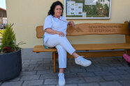 Frau Gschwendtner sitzt auf einer Bank vor dem Seniorenheim