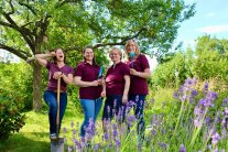 4 studierende Damen stehen mit Gartengeräten in einem Garten