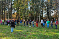 Teilnehmer des Seminars stehen im Wald auf einer grünen Wiese